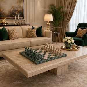 May include: A square chess set featuring a polished green and cream marble board with matching carved stone chess pieces. The set is displayed on a large, rectangular, beige travertine coffee table with a thick, textured stone surface.