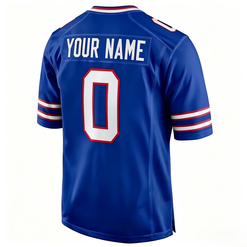 K&ouml;nnte beinhalten: Ein k&ouml;nigsblaues Kurzarmtrikot mit dem Schriftzug YOUR NAME in wei&szlig;en Blockbuchstaben &uuml;ber einer gro&szlig;en wei&szlig;en Nummer 0 mit roter Umrandung. Der Kragen und die &Auml;rmelb&uuml;ndchen sind mit wei&szlig;en und roten Streifen versehen, die Schultern haben wei&szlig;e Akzente.
