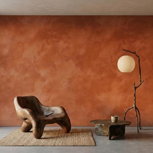 May include: A dark brown organic-shaped wooden armchair sits on a rectangular woven rug. Beside it is a low, irregular wooden coffee table with a small cup and a tall, dark, branch-like floor lamp featuring a round, off-white paper lantern shade.