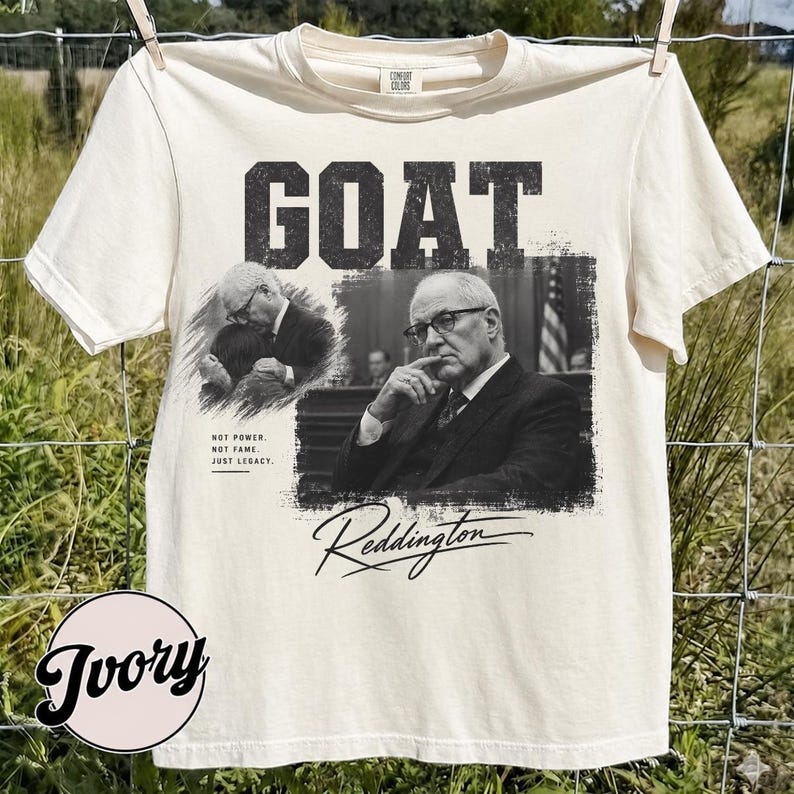May include: An ivory short-sleeve t-shirt featuring a black and white graphic print. The design includes the word GOAT in bold letters, two images of a man in a suit, and the text: NOT POWER, NOT FAME, JUST LEGACY, and the signature Reddington.