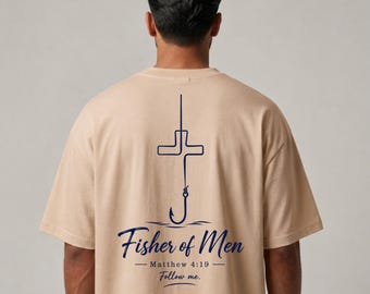 Puede incluir: Una camiseta beige de manga corta con un gráfico azul oscuro en la espalda. El diseño muestra un anzuelo con forma de cruz, con el texto "Fisher of Men", "Matthew 4:19" y "Follow me." impreso en una tipografía azul oscuro cursiva y serif.