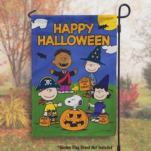 May include: A rectangular garden flag featuring the text HAPPY HALLOWEEN in yellow letters. The design shows five Peanuts characters in costumes, including a pirate, a vampire, a wizard, and a witch, with Snoopy sitting inside a carved orange pumpkin.