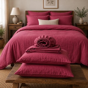 Peut inclure: Une parure de lit magenta profond comprenant une housse de couette, deux taies d'oreiller et un drap-housse. L'ensemble est composé d'un tissu texturé. La housse de couette recouvre un lit, tandis que les taies et le drap sont pliés sur une table.