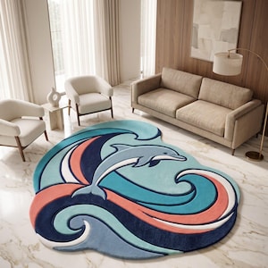 May include: An irregularly shaped area rug featuring a central light blue dolphin leaping over stylised ocean waves. The design incorporates layered curves in shades of navy blue, teal, light blue, coral pink, and white with a textured pile finish.