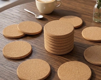 May include: A set of round, light brown cork coasters. The collection includes one tall vertical stack of eight coasters and several individual coasters arranged in a circular pattern around the stack on a dark brown wooden surface.