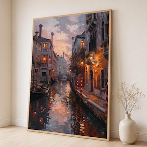 May include: A vertical framed wall art print depicting a Venetian canal scene at dusk. The painting features historic buildings with warm glowing windows, a gondola floating on the water, and reflections of the sunset sky on the canal surface.