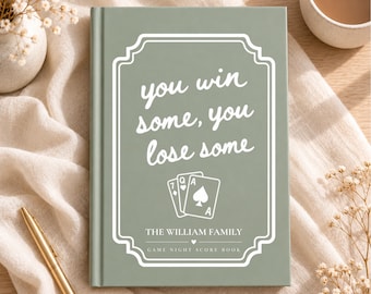 Könnte beinhalten: Ein salbeigrünes Hardcover-Spielabend-Punktbuch mit weißem Text, der you win some, you lose some lautet, einer Abbildung von drei Spielkarten, dem Text THE WILLIAM FAMILY und GAME NIGHT SCORE BOOK.