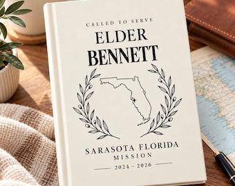 Könnte beinhalten: Ein cremefarbenes Notizbuch mit festem Einband und schwarzem Text CALLED TO SERVE ELDER BENNETT, einer Strichzeichnung von Florida mit einem Sternsymbol sowie dem Text SARASOTA FLORIDA MISSION 2024-2026, umrahmt von zwei Olivenzweigen.