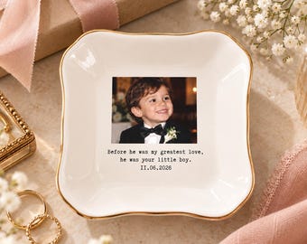 Könnte beinhalten: Eine quadratische weiße Keramikschale mit goldfarbenem Rand. In der Mitte befindet sich ein Foto eines kleinen Jungen im Smoking mit Fliege, darunter der Text: Before he was my greatest love, he was your little boy. 11.06.2026 aufgedruckt.