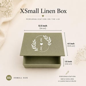 May include: An extra small olive green linen box with a white circular leaf design and the letter E on the lid. The box measures 5.5 inches wide, 4.1 inches deep, and 1.5 inches high. The text XSmall Linen Box and Personalization on the lid appear.