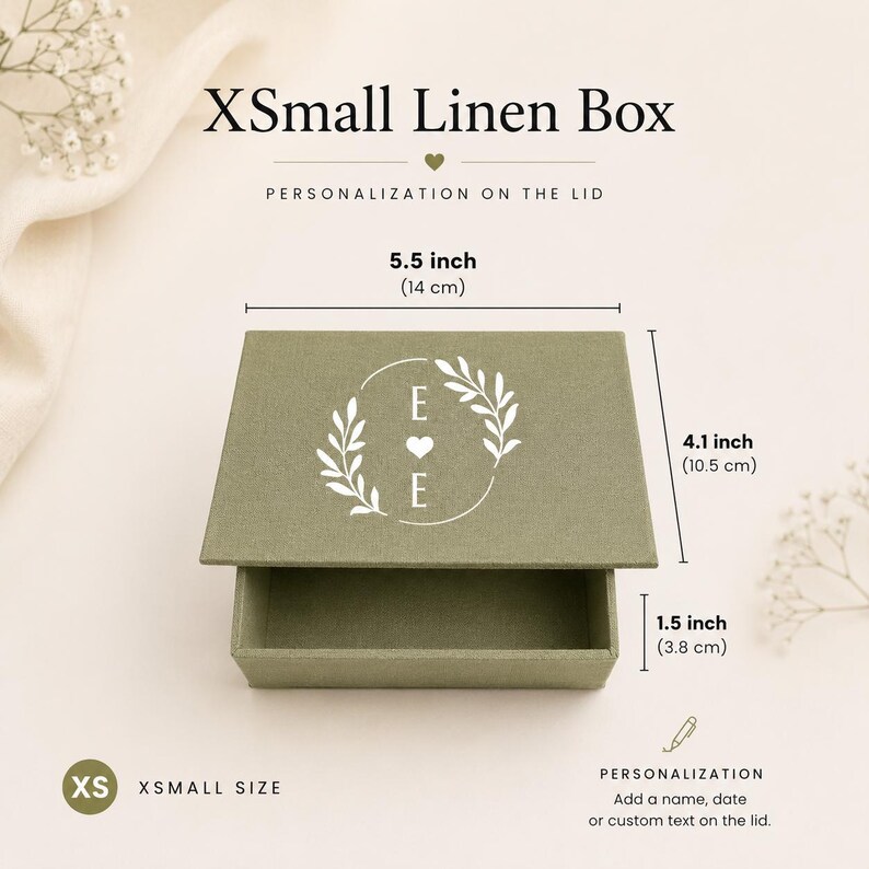 May include: An extra small olive green linen box with a white circular leaf design and the letter E on the lid. The box measures 5.5 inches wide, 4.1 inches deep, and 1.5 inches high. The text XSmall Linen Box and Personalization on the lid appear.