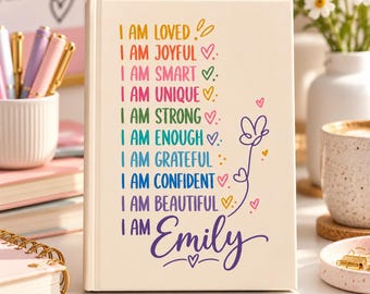 Könnte beinhalten: Ein cremefarbenes Notizbuch mit festem Einband und buntem Text: I AM LOVED, I AM JOYFUL, I AM SMART, I AM UNIQUE, I AM STRONG, I AM ENOUGH, I AM GRATEFUL, I AM CONFIDENT, I AM BEAUTIFUL, I AM Emily, verziert mit kleinen Herz- und Blumensymbolen.