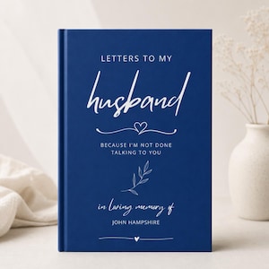 May include: A deep blue hardback journal with white text that reads: LETTERS TO MY husband BECAUSE I'M NOT DONE TALKING TO YOU in loving memory of JOHN HAMPSHIRE. The cover features a small heart icon, a delicate leaf illustration, and lines.