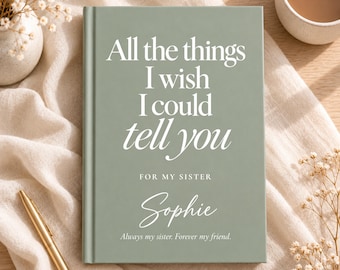 Könnte beinhalten: Ein salbeigrünes Notizbuch mit festem Einband und weißem Text: All the things I wish I could tell you, FOR MY SISTER, Sophie, Always my sister. Forever my friend. Das Buch liegt auf einem weißen Stoffuntergrund neben einem goldenen Stift.