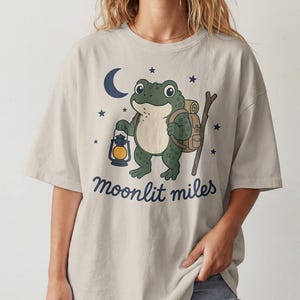 Maglietta da trekking con rana carina, maglietta da campeggio in stile cottagecore, maglietta grafica "Moonlit Miles", regalo per escursionisti notturni, natura goblincore, souvenir per backpacker con rospo
