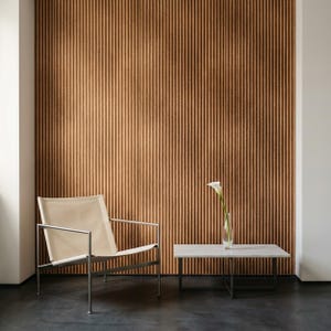 May include: A lounge chair with a cream-colored fabric seat and a thin metal frame, positioned next to a rectangular stone-topped coffee table with a metal base. A single white calla lily in a glass vase sits on the table against a ribbed wall.
