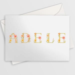 May include: A white greeting card featuring the name ADELE in large, pale yellow capital letters. Each letter is decorated with delicate watercolor illustrations of small pink and yellow flowers, green leaves, and thin stems.