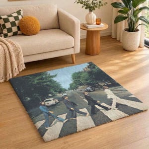 Peut inclure: Un tapis rectangulaire orné d'une impression représentant quatre silhouettes traversant un passage piéton sur une rue urbaine. L'image reproduit une pochette d'album classique avec des arbres, une voiture blanche et des marquages au sol.