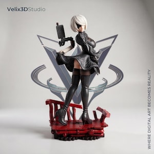 May include: A collectible figurine of a character with short white hair and a black blindfold, wearing a black dress with intricate patterns and high-heeled boots. The figure holds a black firearm and stands on a red, weathered, rubble-like base.