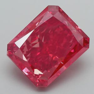Puede incluir: Una gema de corte rectangular vibrante con un tono rojo intenso y múltiples facetas que crean una superficie compleja y reflectante. La piedra presenta bordes afilados y una forma geométrica simétrica, mostrando una saturación de color intensa.