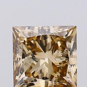 May include: A square-cut gemstone with a light brown, champagne-colored hue. The stone features a faceted surface with a geometric pattern that creates sharp, angular reflections and a high level of brilliance across its entire top surface.