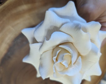 May include: A single, white, fabric rose with a delicate, layered design. The rose is crafted with intricate details and has a soft, velvety texture.