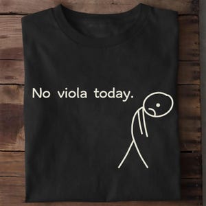 May include: A black short-sleeved t-shirt featuring the white text "No viola today." printed on the left side. To the right of the text is a simple white line drawing of a sad stick figure with a rounded head, curved mouth, and downward posture.