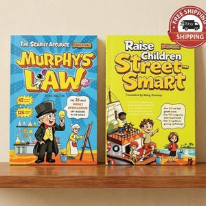 May include: Two books with illustrated covers. The left book is blue with the title "The Scarily Accurate Murphy's Law" and a cartoon man in a top hat. The right book is yellow with the title "Raise Children Street-Smart" and a cartoon boat scene.