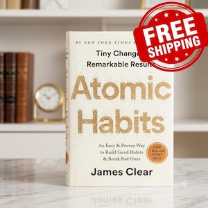 May include: A hardcover book titled Atomic Habits by James Clear with a cream-colored cover and gold glitter lettering. The text reads Tiny Changes, Remarkable Results, An Easy & Proven Way to Build Good Habits & Break Bad Ones, and Over 1 Million Copies Sold.