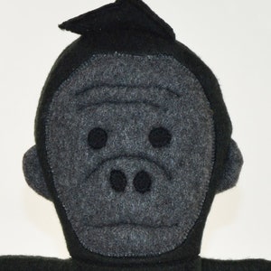 May include: A gray felt gorilla puppet with black felt eyes and a black felt nose. The puppet has a black felt head and a gray felt face.