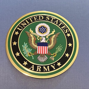 May include: A circular emblem featuring the United States Army seal. The design includes a central eagle with outstretched wings, a shield, and the text "UNITED STATES ARMY" around the perimeter. The emblem is primarily green, gold, and red.
