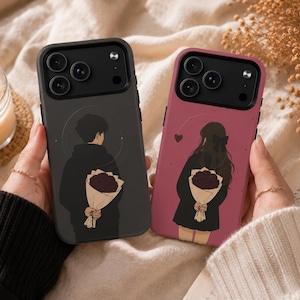 May include: Two smartphone cases featuring illustrated figures holding bouquets behind their backs. The left case is dark gray with a male figure, and the right case is dusty rose with a female figure. Both cases have black camera cutouts.