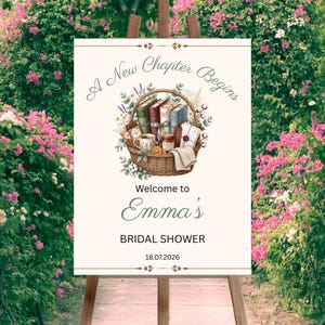 Pode incluir: Uma placa retangular num cavalete de madeira com o texto A New Chapter Begins, Welcome to Emma's BRIDAL SHOWER e 18.07.2026. O gráfico central mostra uma cesta de vime cheia de livros, uma caneca, um frasco e flores em tons suaves.