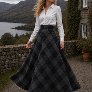 Könnte beinhalten: Ein langer, hoch taillierter, bodenlanger Rock mit einem dunkelgrauen und schwarzen Karomuster und ausgestellter Silhouette, kombiniert mit einem weißen, langärmeligen Hemd mit Knopfleiste und schwarzen Stiefeletten für ein klassisches Outfit.