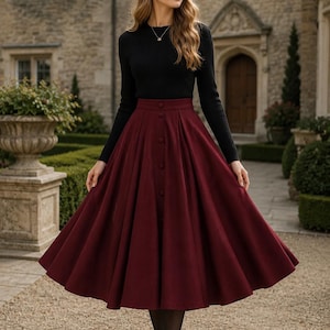 May include: A long-sleeved black ribbed jumper paired with a high-waisted, calf-length burgundy skirt. The skirt features a central vertical row of matching buttons, a structured waistband, and a full, pleated silhouette that flares outward.