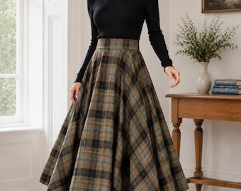 May include: A long-sleeved black crew neck top paired with a high-waisted, full-length midi skirt featuring a plaid pattern in shades of olive green, brown, black, and yellow. The skirt has a structured waistband and a flared, pleated silhouette.