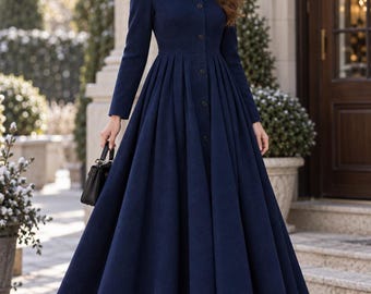 May include: A long-sleeved navy blue coat featuring a fitted bodice, a high neckline, and a full, pleated skirt that reaches the ankles. The coat is fastened with a vertical row of dark buttons down the front and is worn with a black beanie and boots.