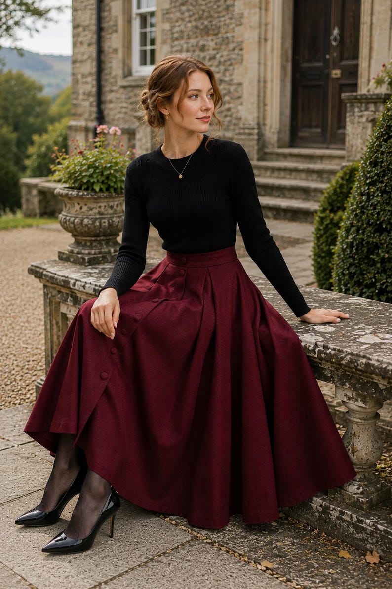 May include: A long, deep burgundy skirt featuring a high waist, a row of matching buttons down the front, and deep pleats, paired with a black long-sleeved ribbed jumper, sheer black tights, and black pointed-toe high-heeled pumps.