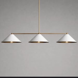 May include: A linear pendant light fixture featuring a thin brass rod suspended from a single vertical stem. The fixture holds three white conical shades, each with a warm light bulb visible underneath, arranged horizontally in a row.
