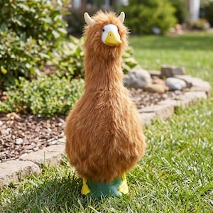 May include: A plush stuffed animal featuring a brown, shaggy, long-haired body with a white face, a yellow beak, and two small, upright, cream-colored horns on top of its head. The creature stands on two yellow webbed feet.
