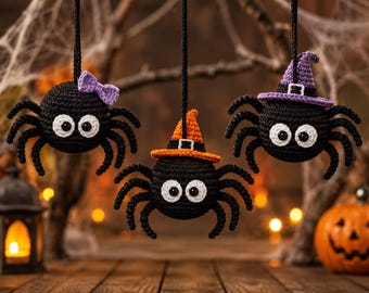 May include: Three crocheted black spider ornaments hanging by black strings. The left spider wears a purple bow, the center spider wears an orange witch hat, and the right spider wears a purple witch hat. Each spider has large white eyes.