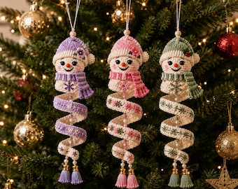 May include: Three crocheted snowman ornaments with spiral bodies in lavender, pink, and sage green. Each snowman wears a matching hat with a small flower and a scarf, featuring embroidered snowflake patterns, hanging beads, and dual tassels at the base.