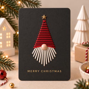 Puede incluir: Una tarjeta de felicitación rectangular negra con un diseño de gnomo bordado. El gnomo tiene un gorro de rayas rojas, una nariz redonda de color beige y una barba blanca hecha de hilo. Una pequeña estrella dorada corona el gorro. El texto MERRY CHRISTMAS está impreso en oro.