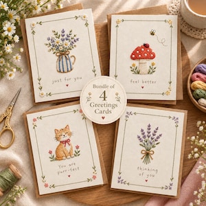 Pode incluir: Um conjunto de quatro cartões de felicitações com desenhos bordados de um ramo de lavanda num jarro às riscas azuis, um cogumelo vermelho com uma joaninha e uma abelha, um gato ruivo e um ramo de lavanda, com texto e borda floral.