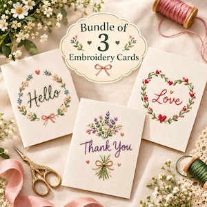 Puede incluir: Un paquete de tres tarjetas de felicitación color crema con diseños bordados. Una tarjeta muestra una corona floral con el texto Hello, otra una corona en forma de corazón con el texto Love, y la tercera un ramo de flores con el texto Thank You.