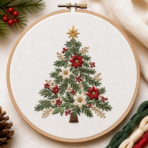 May include: A circular wooden embroidery hoop containing white fabric with a hand-stitched Christmas tree design. The tree features green pine needles, red and white poinsettia flowers, small red berries, and a gold star at the top.
