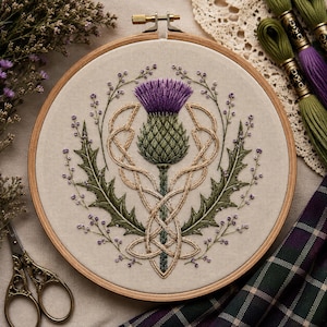 May include: A circular wooden embroidery hoop containing a fabric panel with a hand-stitched design of a purple and green thistle flower. The thistle is framed by intricate beige Celtic knotwork, dark green leaves, and small purple floral sprigs.