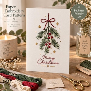 May include: A white greeting card featuring a hand-embroidered design of a green mistletoe sprig with red berries, a red bow, and gold stars. The text Merry Christmas is embroidered in red below the sprig. The card is displayed with embroidery floss.