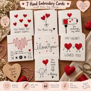May include: Seven square greeting cards featuring hand embroidery designs with red hearts and black text. The cards include phrases like You make my heart happy, You have my heart, You recharge my soul, Our Love Story, I love you, and You have made my life a blessing. The cards measure 12.7x17.8 cm.
