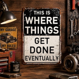 May include: A rectangular metal sign with a distressed finish featuring the black and white text THIS IS WHERE THINGS GET DONE EVENTUALLY. The sign has a black upper section and a white lower section with visible rust-like edges on the corners.